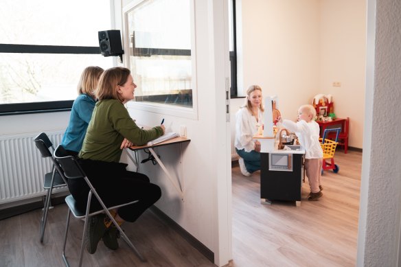 Observatie taalonderzoekers met spelend kind en moeder