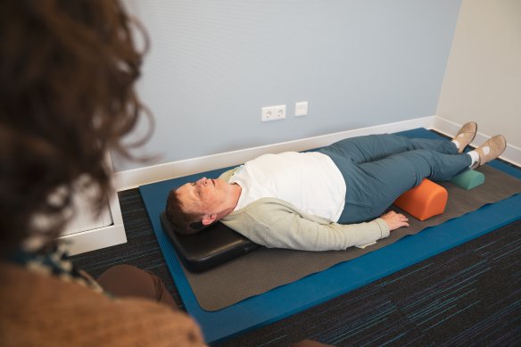 Vrouw krijgt tinnitustherapie op yogamat