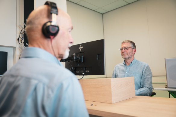 Audioloog doet gehooronderzoek bij man met koptelefoon op