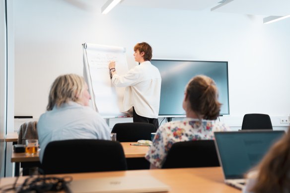 Docent die noteert op een flipover met studenten die kijken